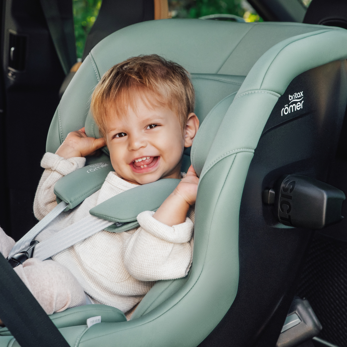 Smiling toddler secured in the MAX-SAFE PRO car seat in Jade Green green inside a vehicle.